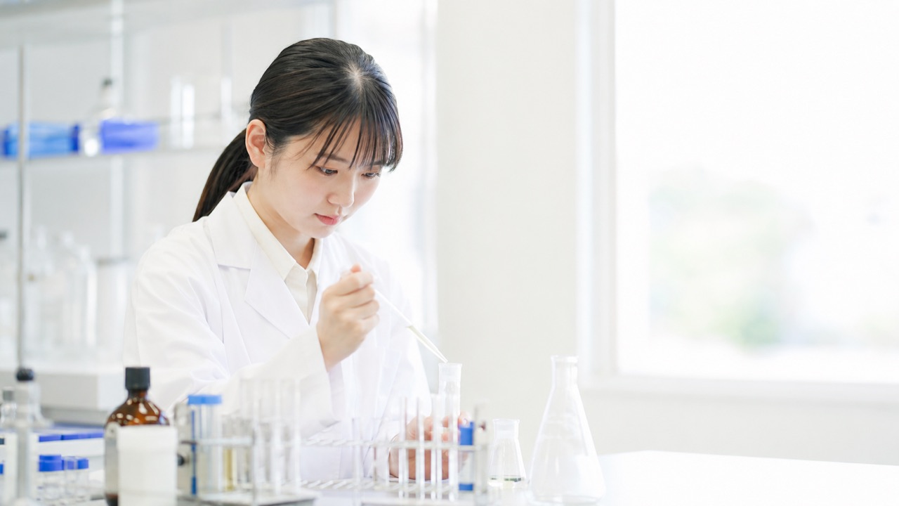 明るい実験室で白衣を着て学ぶ薬学部の学生