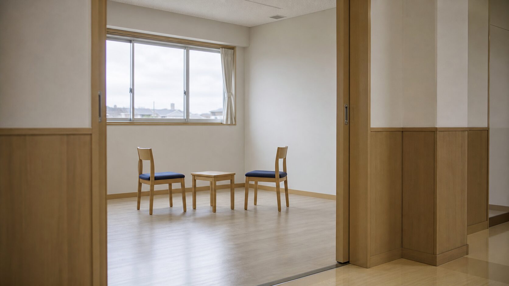 引き戸越しに見える小教室。向かい合う椅子2脚と小さな机